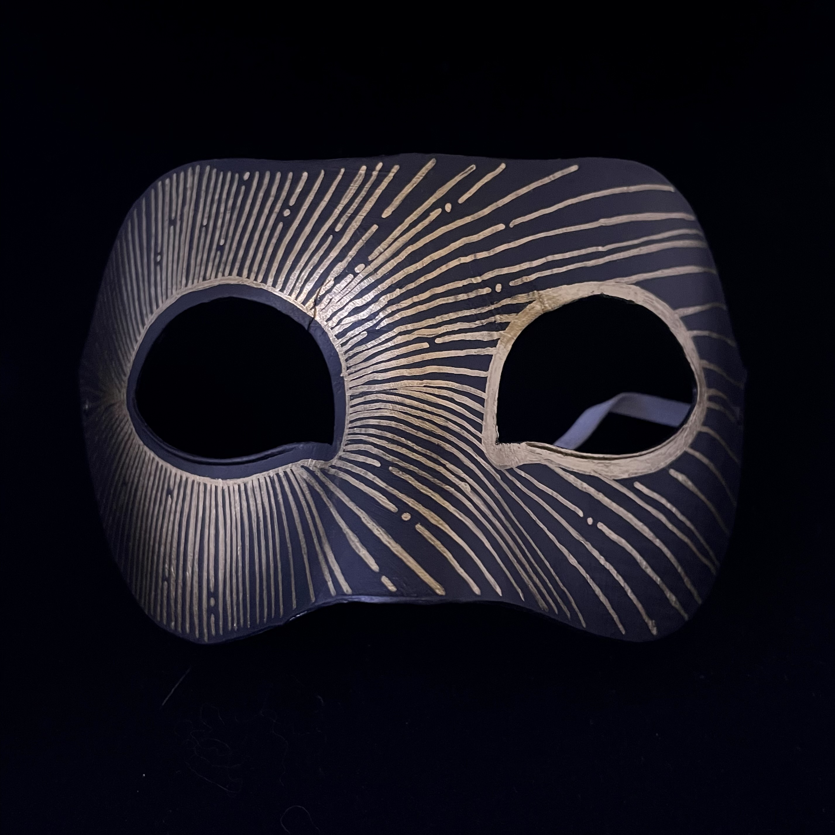 black mask with a gold linear pattern