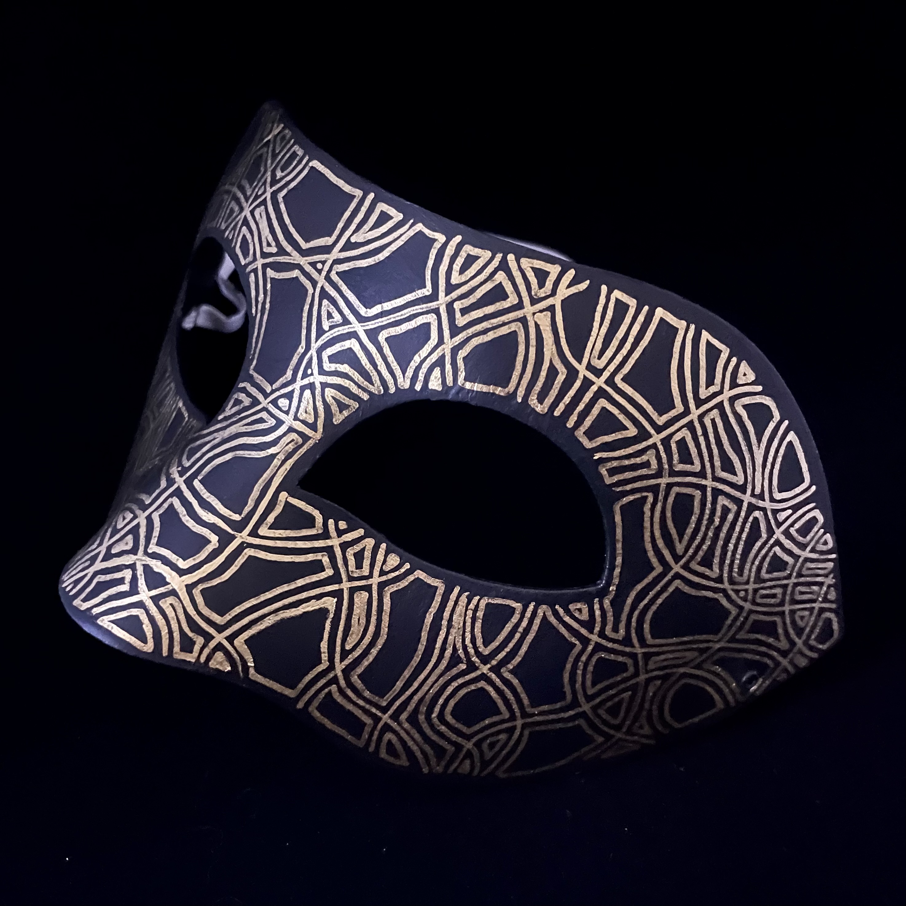 black mask with a gold map-like pattern