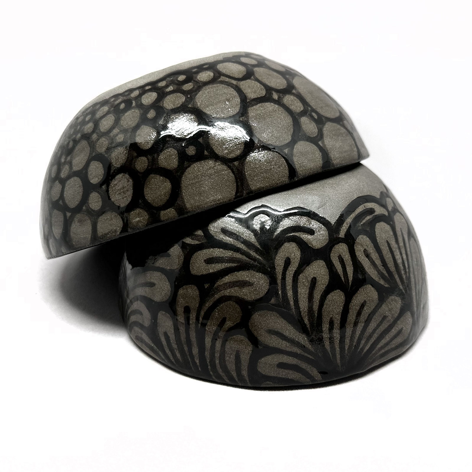 a dark grey ceramic plate with wave-like patterns glazed in black