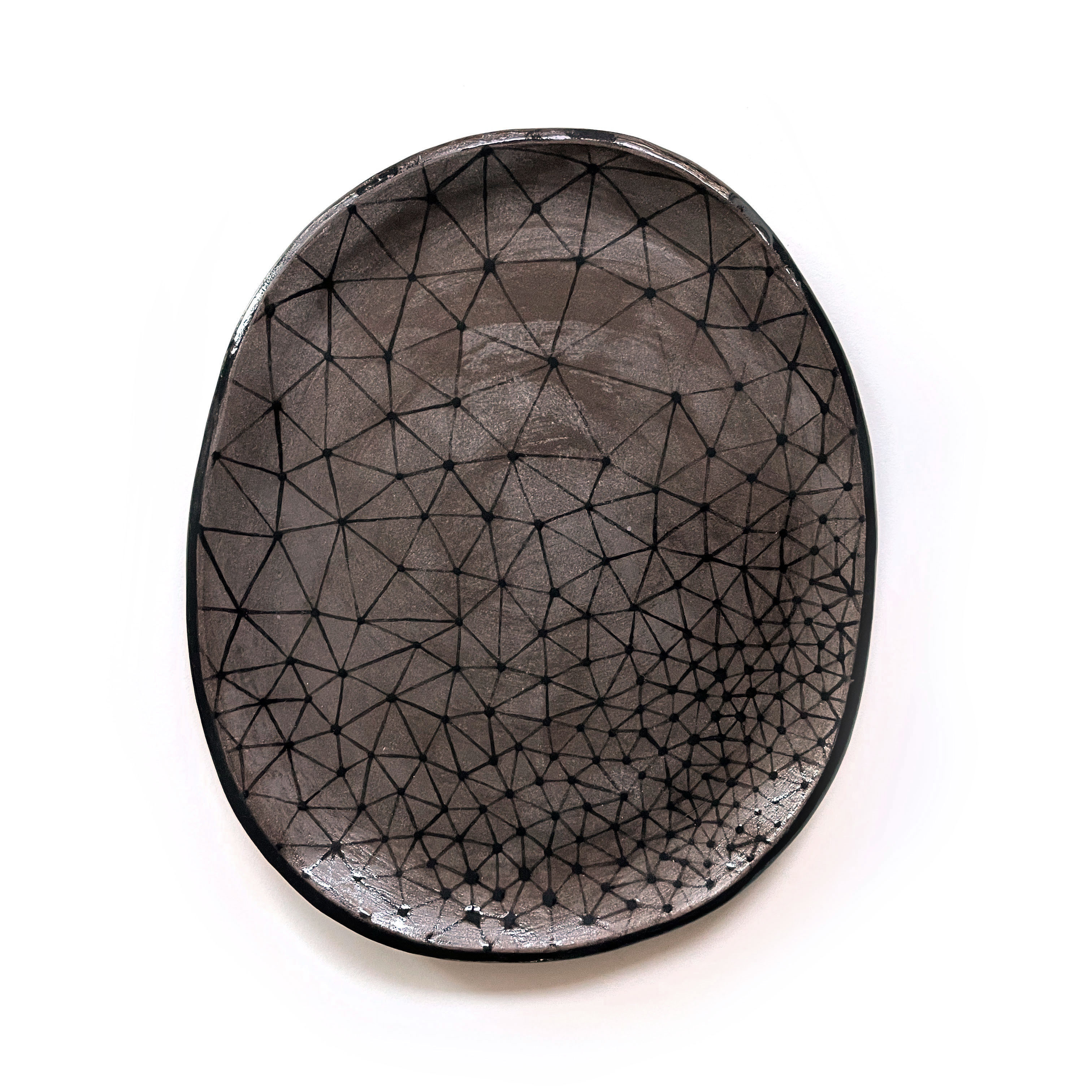 a dark grey ceramic plate with constellation-like patterns glazed in black